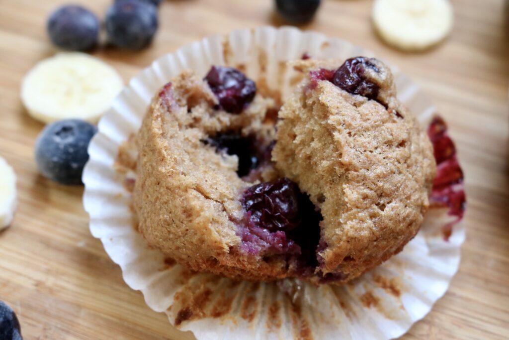 fresh milled blueberry banana muffin torn in half sitting on a counter top