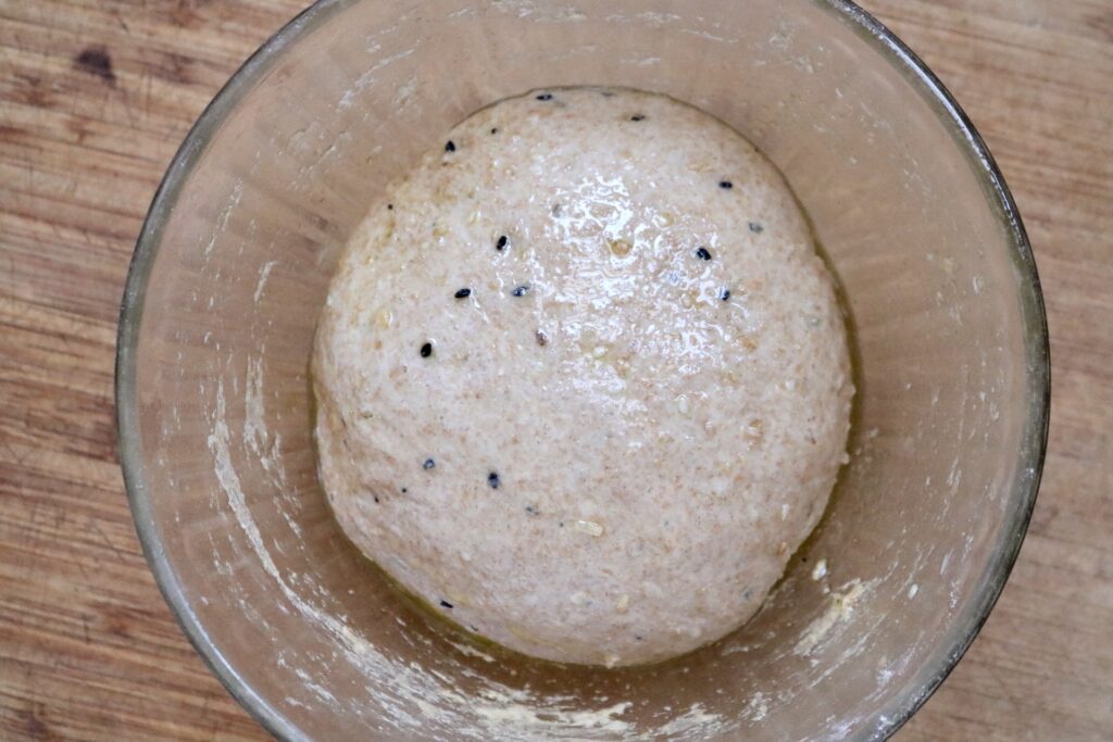 healthy whole grain everything bagel dough in glass bowl