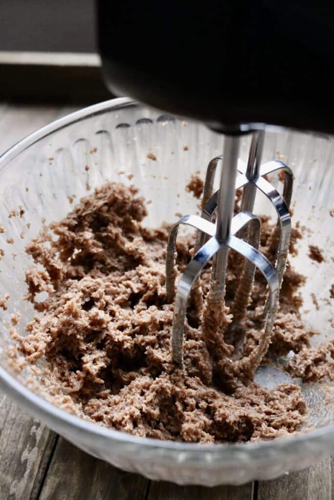 coconut sugar and coconut oil in a bowl being mixed with electric beaters