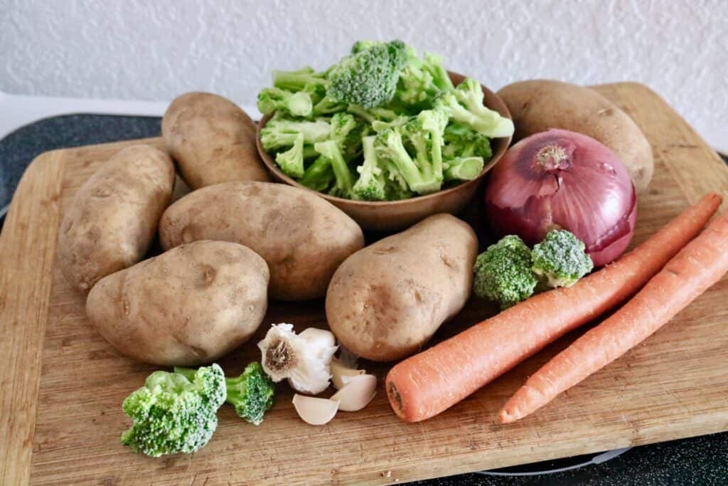 Creamy potato vegetable soup vegetables on wood board side view