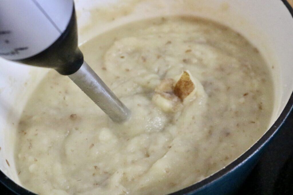 Creamy potato vegetable soup being blended with immersion blender