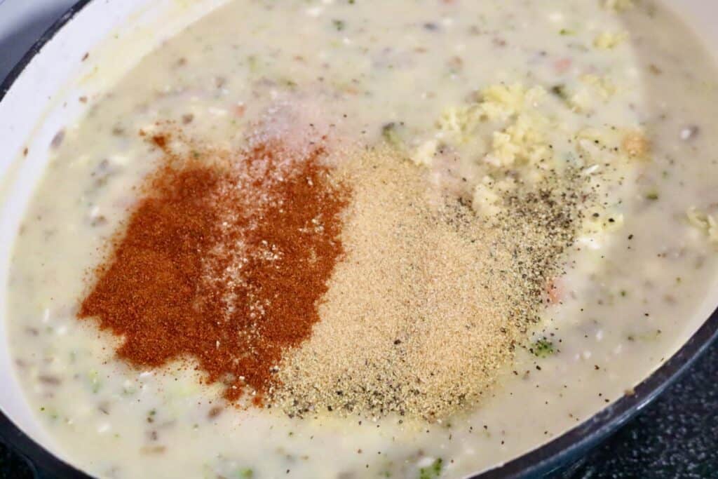 Creamy potato vegetable soup in pot with spices and minced garlic