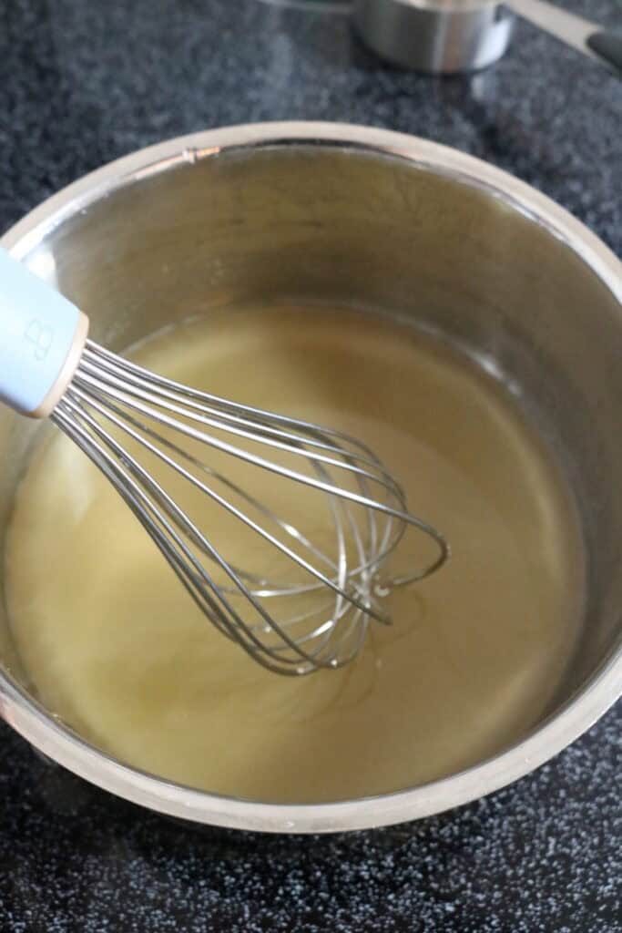 sugar and water in a saucepan being whisked