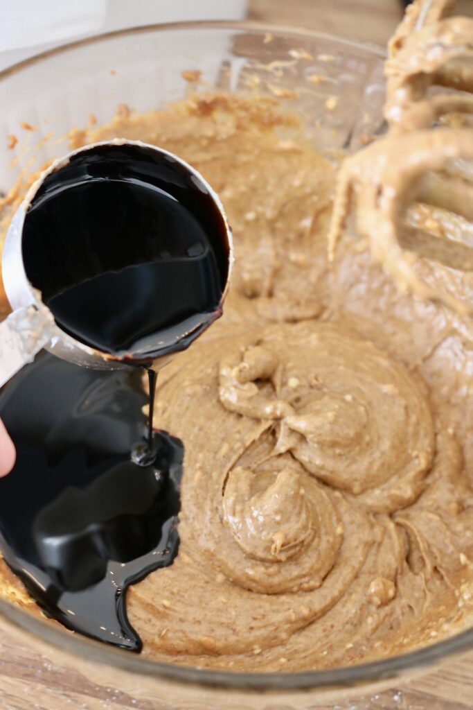 pouring molasses into sourdough whole grain molasses cookie batter