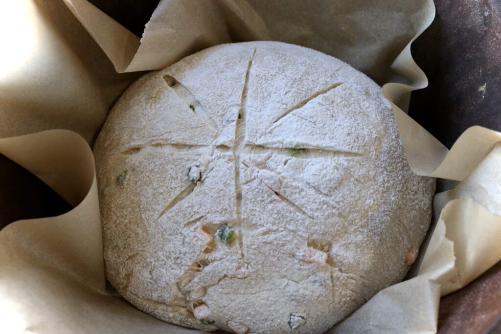Scored Jalapeño cheddar sourdough bread in a dutch oven unbaked