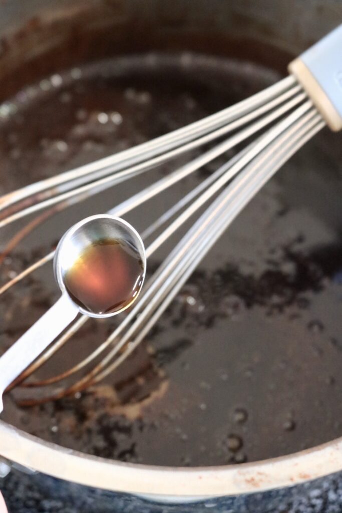 pouring vanilla into a saucepan of chocolate mocha sauce