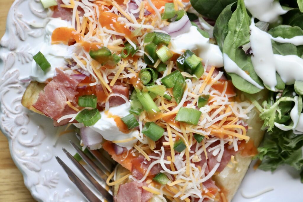 Baked potato bar + topping ideas, potato on a white plate with a salad on the side