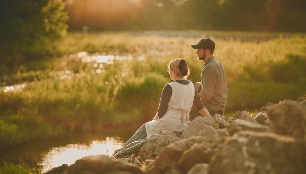how to bless your husband every single day main photo a couple sitting by a stream at sunset