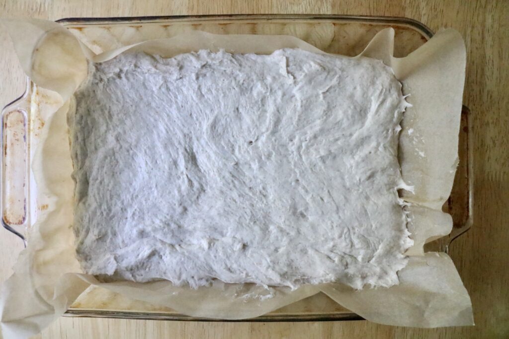 easy sourdough cheese breadstick dough spread out in a baking pan
