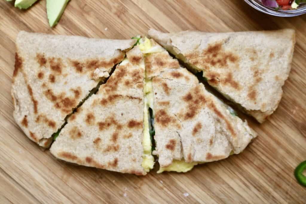 top view of a cooked breakfast quesadilla cut in quarters on a countertop